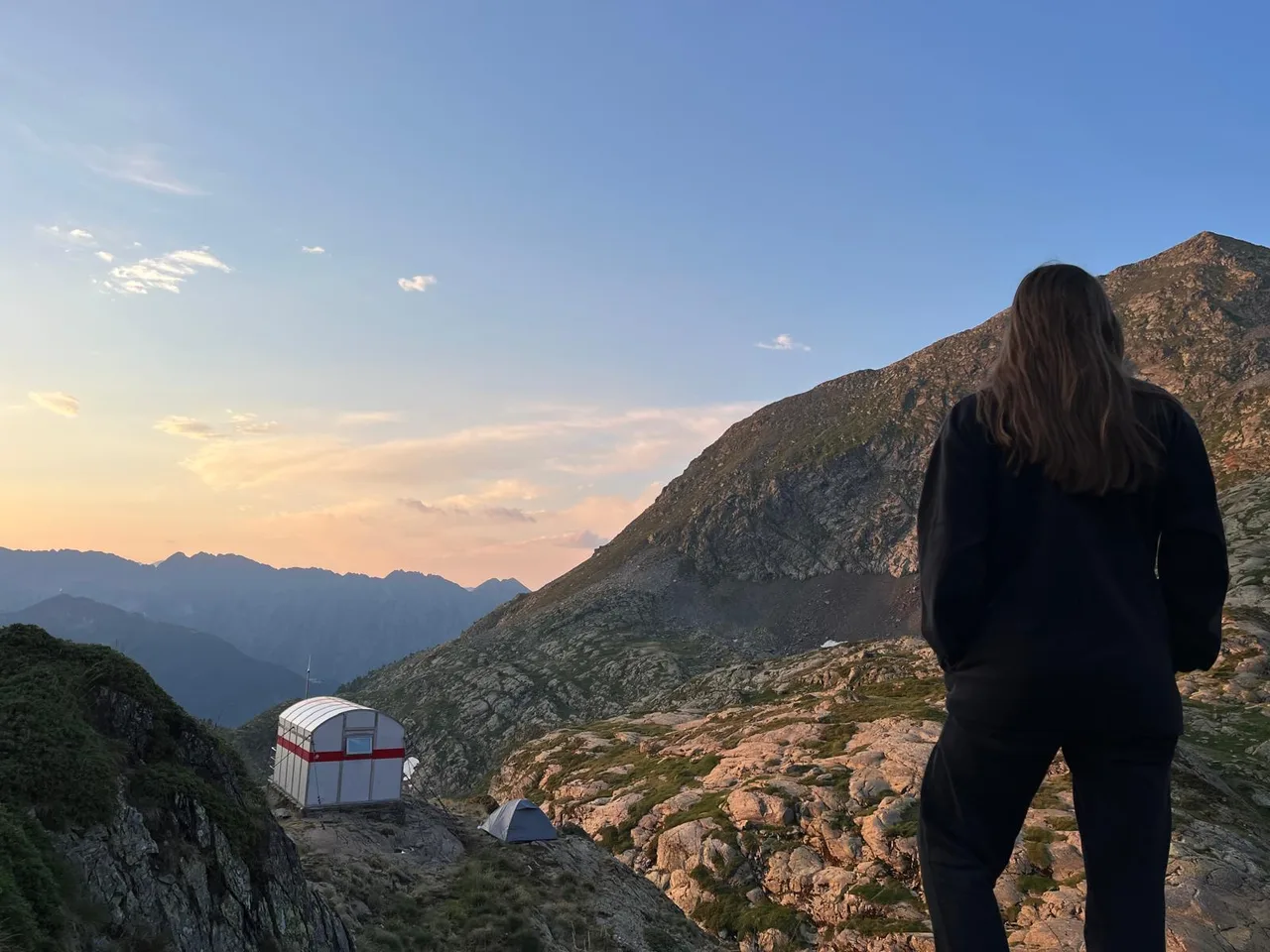 Una jove arriba a un refugi de muntanya al capvespre