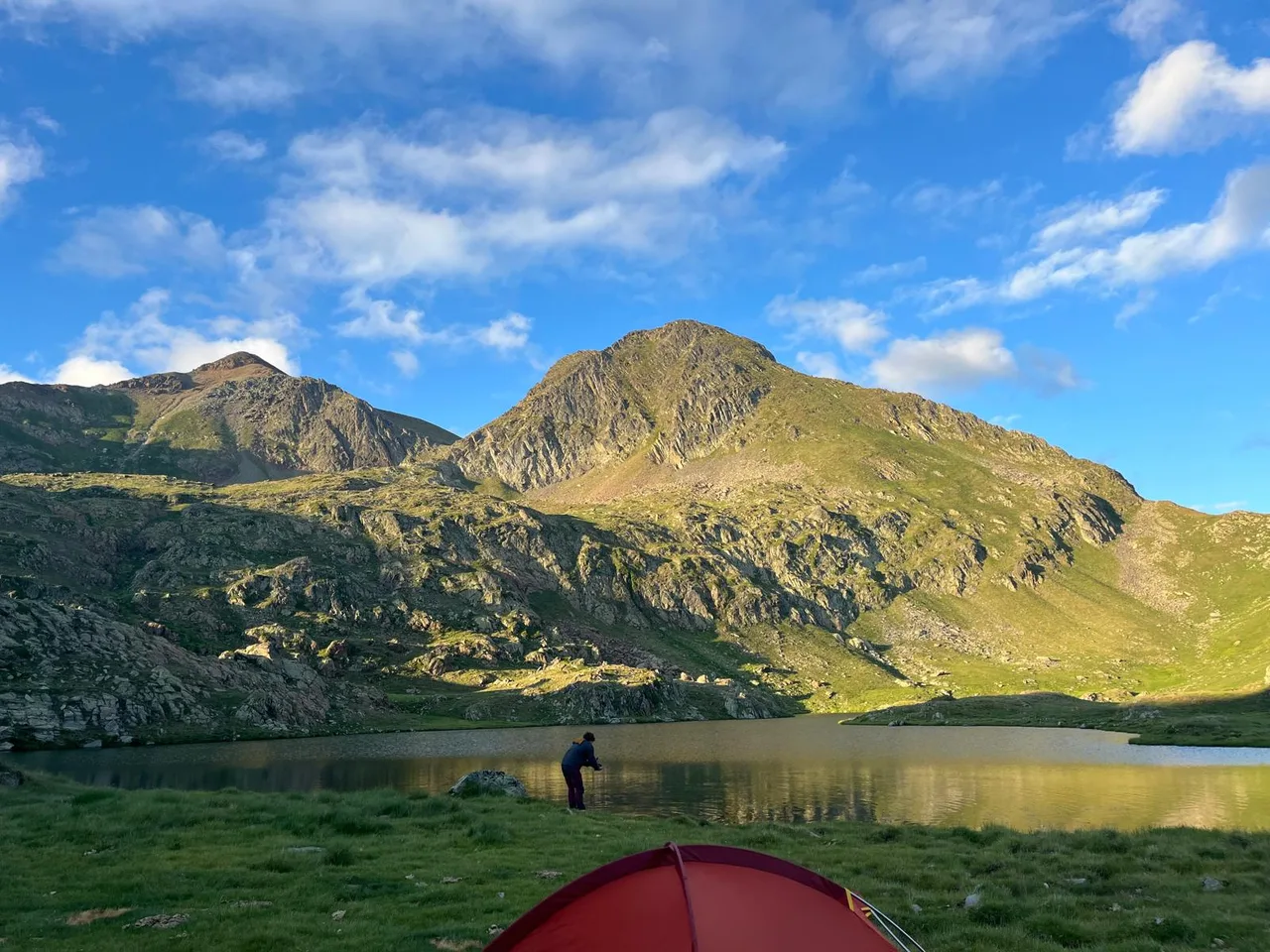 Un estany d’alta muntanya sota cims il·luminats pel sol