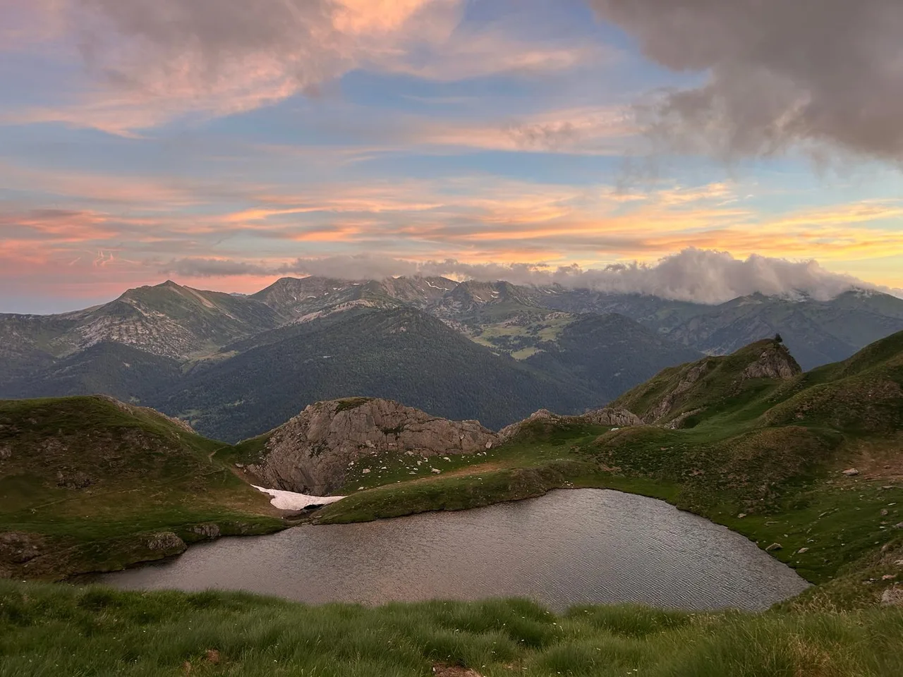 Un estany i les muntanyes sota els colors rosats del capvespre