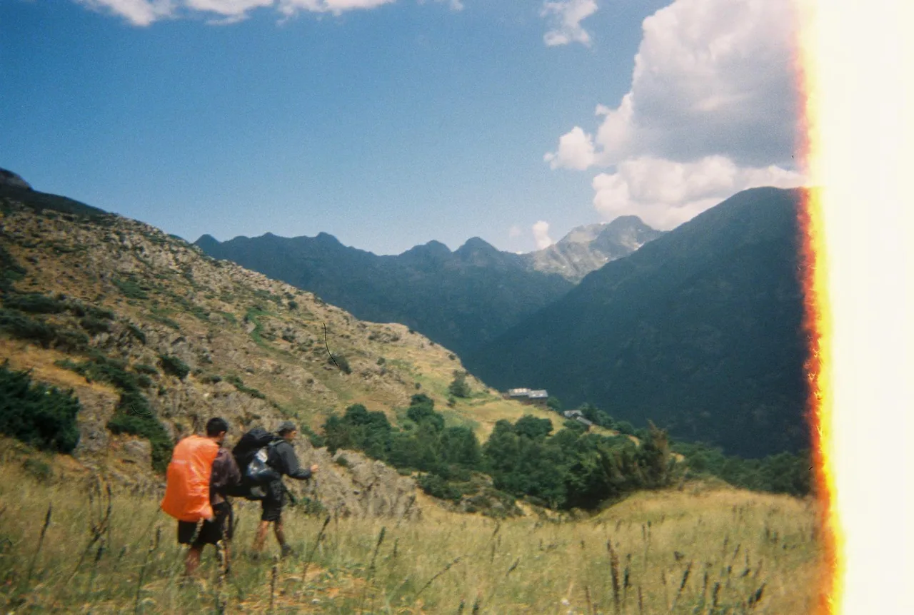 Dos excursionistes avancen per un vessant d’alta muntanya