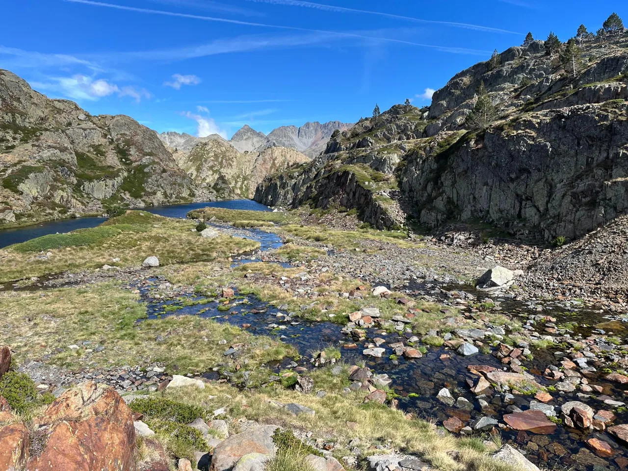 Un rierol travessa un prat entre roques i petits estanys