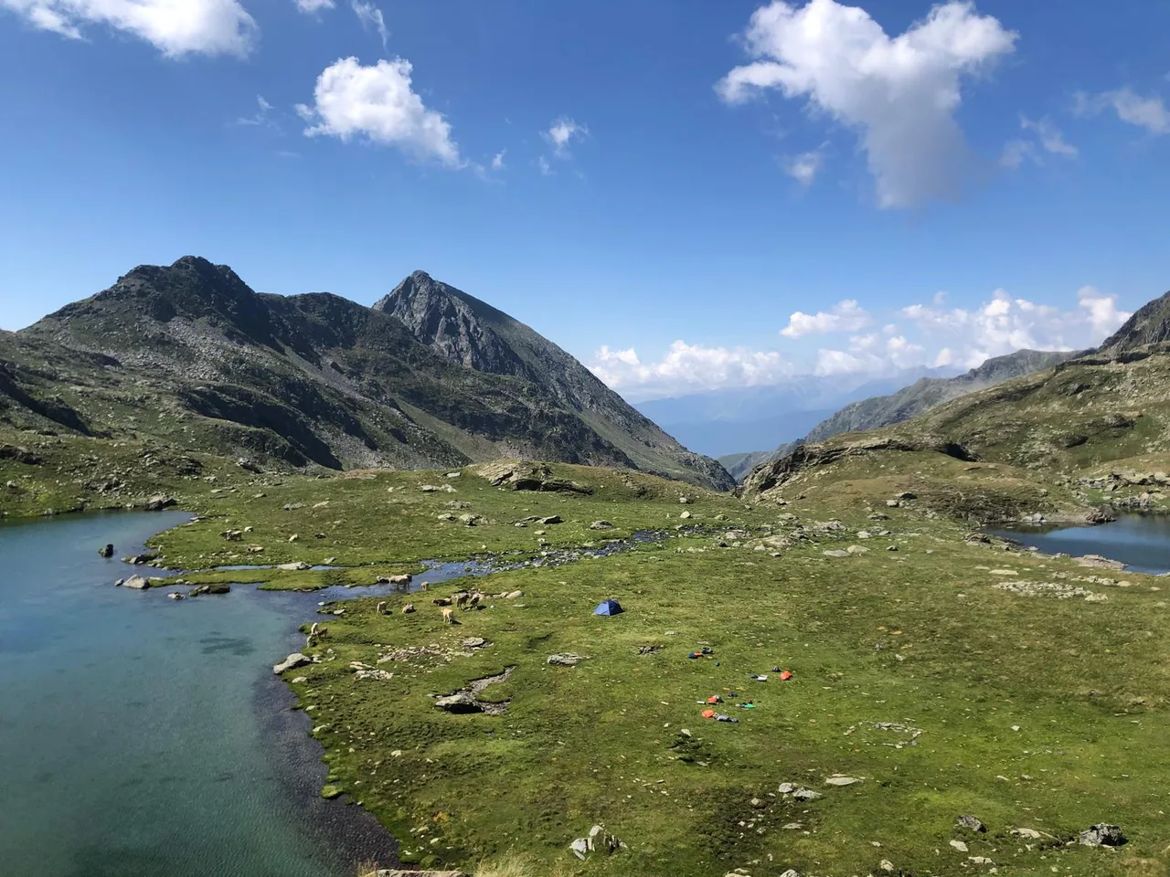 Dos estanys entre prats verds i cims sota un cel blau
